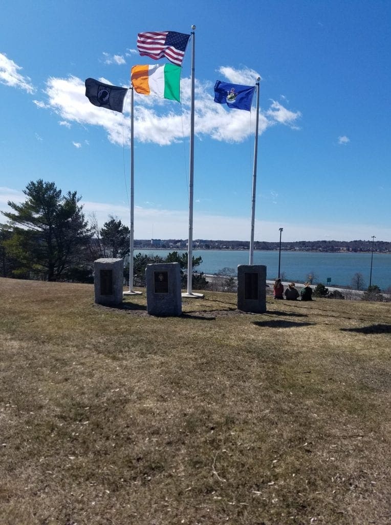 Three stones make up the Loring Memorial in Portland. On the left the POW MIA flag flies, in the middle the American flag over the Irish flag, and on the right the flag of the State of Maine. 
